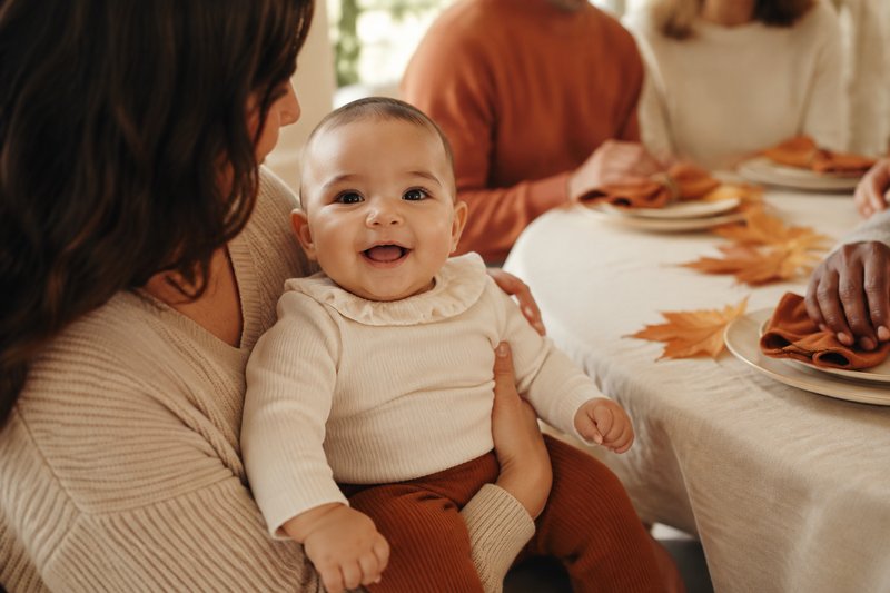 Baby held safely by a caregiver at a warm family Thanksgiving gathering